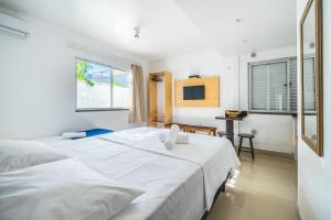 Un dormitorio con una gran cama blanca y una mesa en Pousada Casa de Praia, en Bombinhas