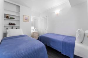 a bedroom with two beds with blue sheets and a chair at Sandpiper Oceanfront 5F in Jacksonville Beach +70 photos