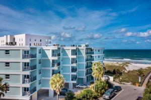 an apartment building with palm trees and the beach at Sandpiper Oceanfront 5F in Jacksonville Beach