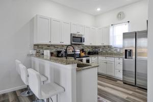 a kitchen with white cabinets and a stainless steel refrigerator at 4BR Villa near Disney & Universal in Orlando, FL in Davenport