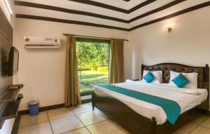 a bedroom with a bed and a large window at Tusk and Roar Corbett Resort, Jim Corbett in Rāmnagar