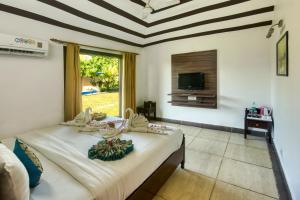 a bedroom with a bed and a tv on a wall at Tusk and Roar Corbett Resort, Jim Corbett in Rāmnagar