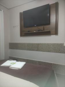 um quarto com uma televisão de ecrã plano na parede em Pousada da Gi Suítes e Turismo em Chapada dos Guimarães