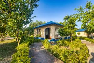 a small house with a blue roof at Tusk and Roar Corbett Resort, Jim Corbett in Rāmnagar