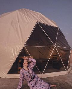 Una donna è seduta di fronte a una tenda di Golden Desert Camp ad Al Wāşil
