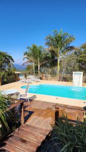 a swimming pool with two chairs and a table at Pousada Kokopelli in Lavras Novas
