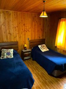 a bedroom with two beds in a wooden cabin at Portal Costanera Caburgua in Caburgua