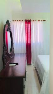 ein Schlafzimmer mit einer Kommode, einem Spiegel und einem Bett in der Unterkunft Cómodo apartamento en Santiago in Licey al Medio