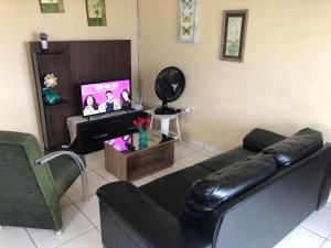 a living room with a black leather couch and a tv at Casa de Praia - Carneiros, Tamandare, Pernambuco in Tamandaré