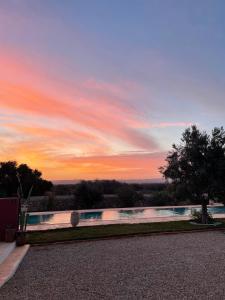 a swimming pool with a sunset in the background at Villa Des Arganiers in Essaouira
