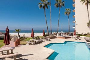 a pool with chairs and umbrellas next to the beach at Oceana Casa Del Mar in Rosarito