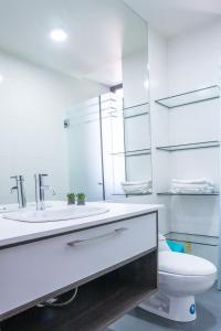 a white bathroom with a toilet and a sink at Sky Suites - Fantastic Apt in the heart of La Paz in La Paz