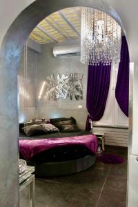 Schlafzimmer mit einem lila Bett und einem Kronleuchter in der Unterkunft Jacuzzi Love SuiteSweetRome in Rom