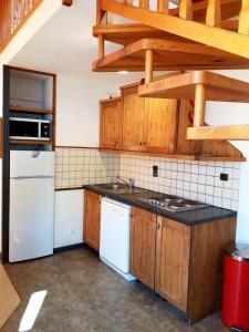 una cocina con electrodomésticos blancos y armarios de madera en Le Napoléon, en Lanslebourg-Mont-Cenis
