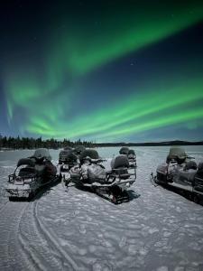 a group of snowboards lined up under the aurora borealis at Camp Caroli Hobbit Hut in Jukkasjärvi