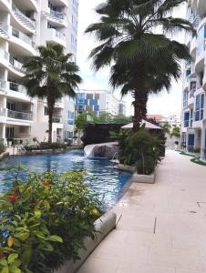 una piscina in una città con palme e edifici di Grand Avenue Pattaya a Centro di Pattaya