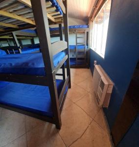 a room with three bunk beds and a window at Pousada Paraíso das Conchas na praia do Peró Cabo Frio RJ in Cabo Frio