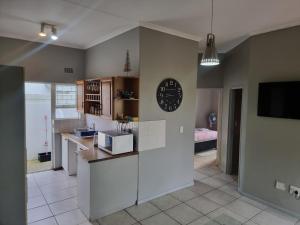 Una cocina con gabinetes blancos y un reloj en la pared. en Strawberry fields Tranquility, en Ciudad del Cabo