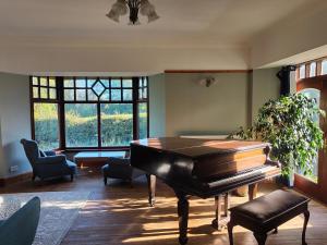 a living room with a piano and a table at The Mill Lade - Hidden House in Arbroath