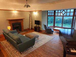 a living room with a couch and chairs and a piano at The Mill Lade - Hidden House in Arbroath