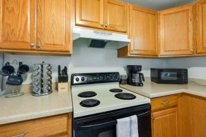 een keuken met een zwart-witte kachel en houten kasten bij Cedar Rapids Vacation Rental 2 Mi to Downtown! in Cedar Rapids