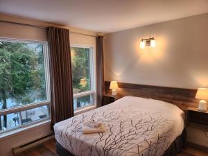 a bedroom with a bed and two windows at Auberge Morritt in Mont-Tremblant