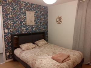 a bedroom with a bed with a floral wallpaper at Gîte le 3M Sainte-mère-église in Sainte-Mère-Église
