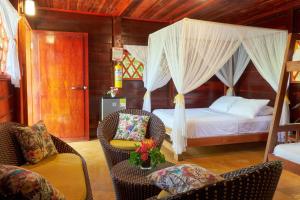 a bedroom with a bed with curtains and chairs at Playa Los Angeles in Los Naranjos