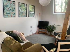ein Wohnzimmer mit einem Sofa und einem Flachbild-TV in der Unterkunft The Studio in Beeston