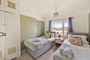 um quarto com 2 camas e uma janela em BridgeCity 3 bed House in Maidstone Town Centre em Kent