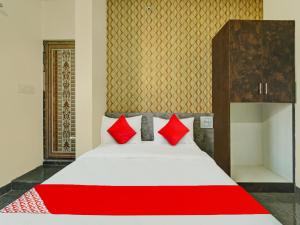 a bed with red pillows in a room at OYO Flagship Mathrushree Lodge in Yelahanka