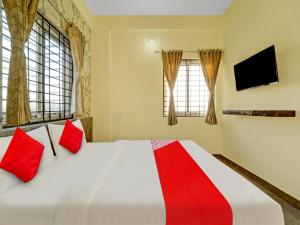 a bedroom with a large white bed with red pillows at OYO Flagship Mathrushree Lodge in Yelahanka