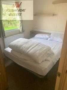 uma cama grande com lençóis brancos e uma janela em Issacs Retreat Skipsea Sands em Ulrome