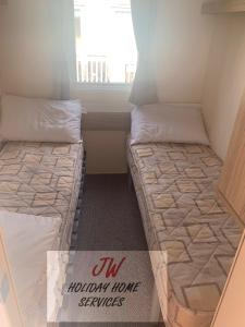 2 camas en una habitación pequeña con ventana en Issacs Retreat Skipsea Sands, en Ulrome