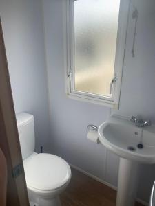 a white bathroom with a toilet and a sink at Issacs Retreat Skipsea Sands in Ulrome