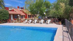 a group of white chairs sitting next to a swimming pool at Cabañas Rincón Potrero in Potrero de los Funes