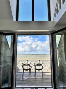 2 chaises assises sur un balcon donnant sur une fenêtre dans l'établissement Le Crotoy - Entre ciel et mer, au Crotoy