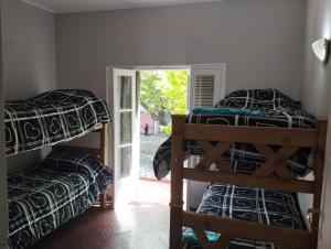 a room with three bunk beds and a door to a yard at HOSTAL HOUSE REYMON,habitaciones privadas" precio por persona" in Mendoza