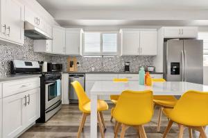 a kitchen with a white table and yellow chairs at Fun Mid-City New Home Sleeps 10 Near USC/DTLA/Expo in Los Angeles