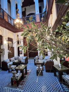 a lobby with tables and a tree in the middle at Dar Labchara in Fez