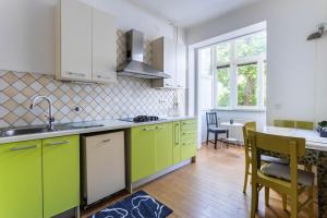 a kitchen with green and white cabinets and a table at Apartment Ana By Blue Apartments in Zagreb