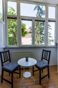 two chairs and a table in a room with windows at Apartment Ana By Blue Apartments in Zagreb