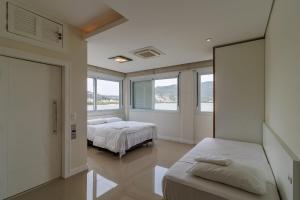 1 dormitorio con 2 camas y 2 ventanas en Casa à beira-mar com piscina Floripa-SC RJD156 en Florianópolis