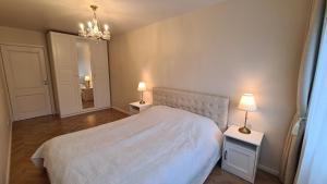 a bedroom with a white bed and two tables with lamps at near the old town in Kaunas