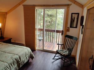 1 dormitorio con 1 cama, 1 silla y balcón en Casa Verde - Near Zion & Bryce National Park en Duck Creek Village