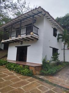 Una casa blanca con un balcón en el lateral. en Cabañas Coloniales con Entorno Natural en Barichara en Barichara