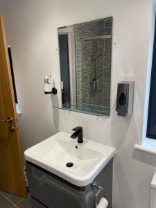 uma casa de banho branca com um lavatório e um espelho em Warm welcoming Home em Manchester