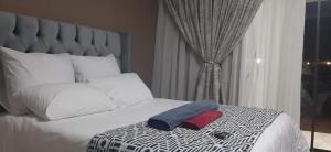 una camera con un letto bianco e una grande testiera del letto di Soma Guesthouse a Groblersdal
