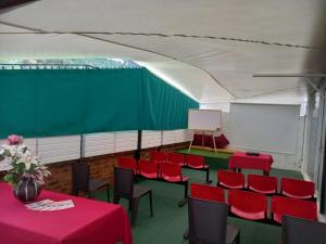 a conference room with red tables and chairs and a screen at HOTEL BOUTIQUE 14 LANCEROS in Paipa