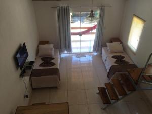 a living room with two beds and a television at Flats Maraú - Taipu de Fora Bahia in Marau
